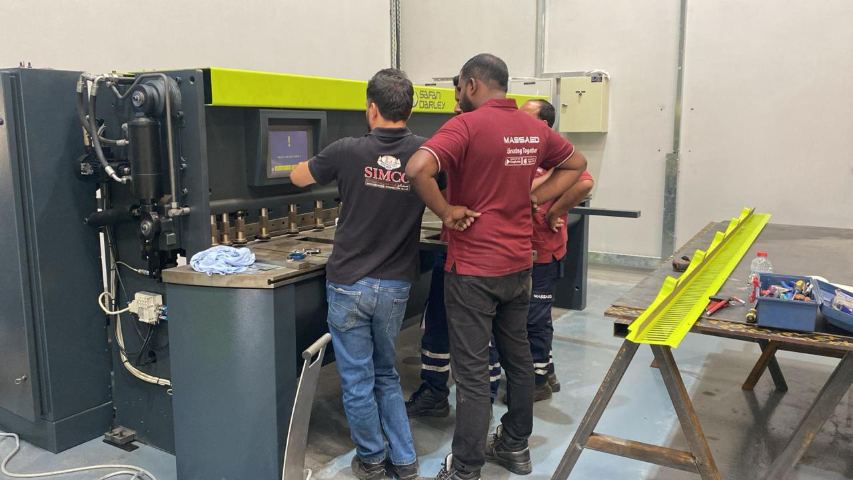 MASSAED team setting up the CNC shearing machine that cuts metal sheet for cladding panels